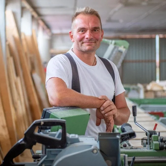 Geschäftsführer Marco Hohbein Geschäftsführer Marco Hohbein steht in einer Werkstatt, umgeben von Maschinen und Holz.