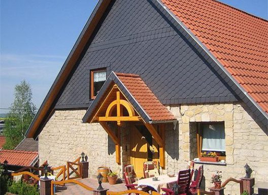 Haus mit Spitzdach und verkleideter Giebelseite aus Schiefer.