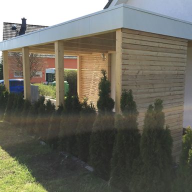 Holzveranda mit Säulen und Blick auf angelegte Hecken im Garten.