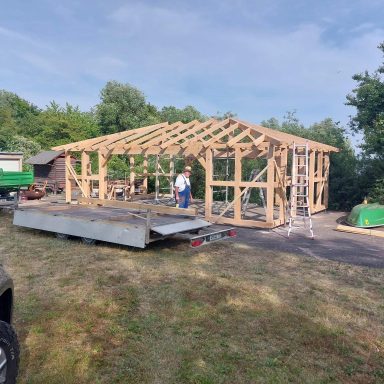 Holzrahmenbau eines Gebäudes mit Handwerkern auf einer Baustelle im Freien.
